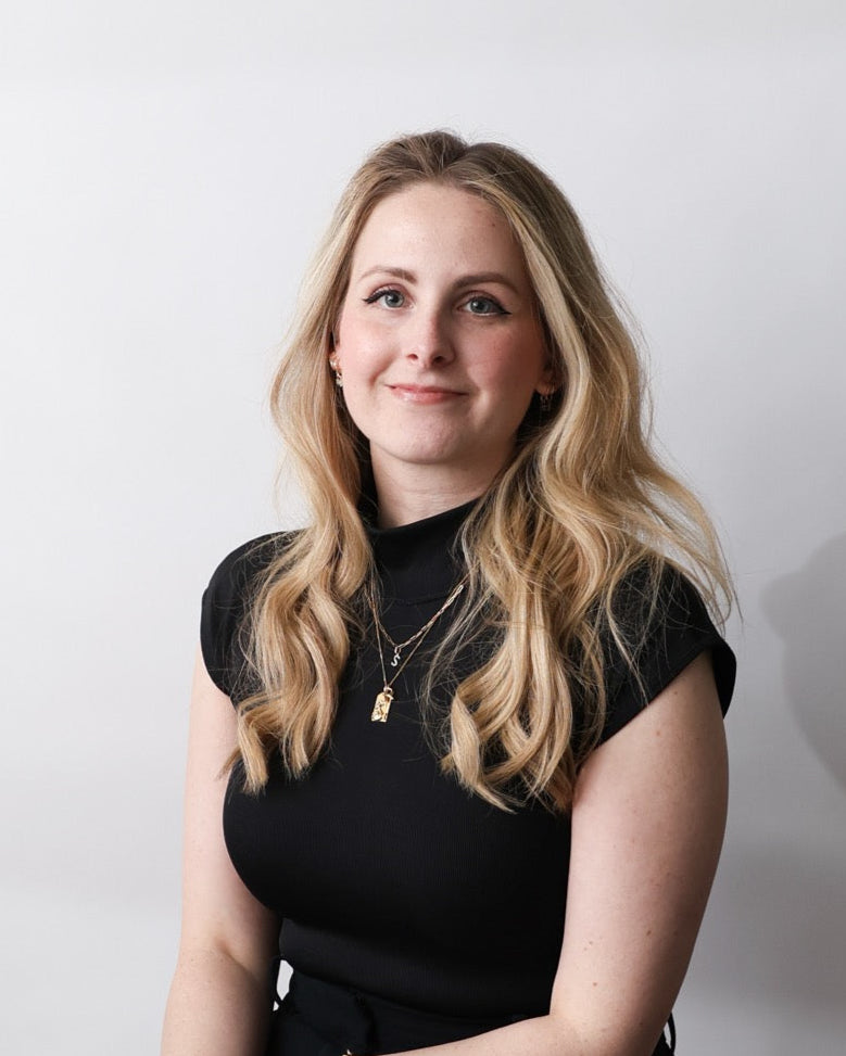 Caitie Rachar in a black dress sitting against a white background