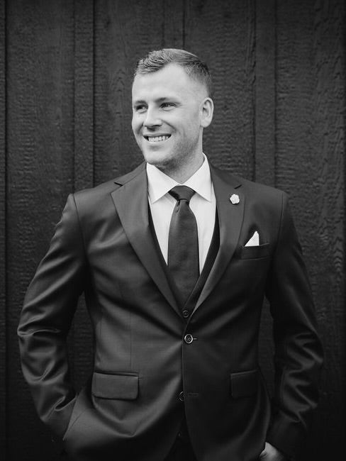 Man in a suit standing against a textured dark wall
