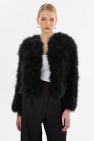 Woman wearing a black feathered jacket on a white background