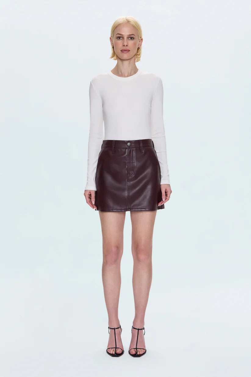Woman wearing a white long-sleeve top and brown leather skirt on a white background