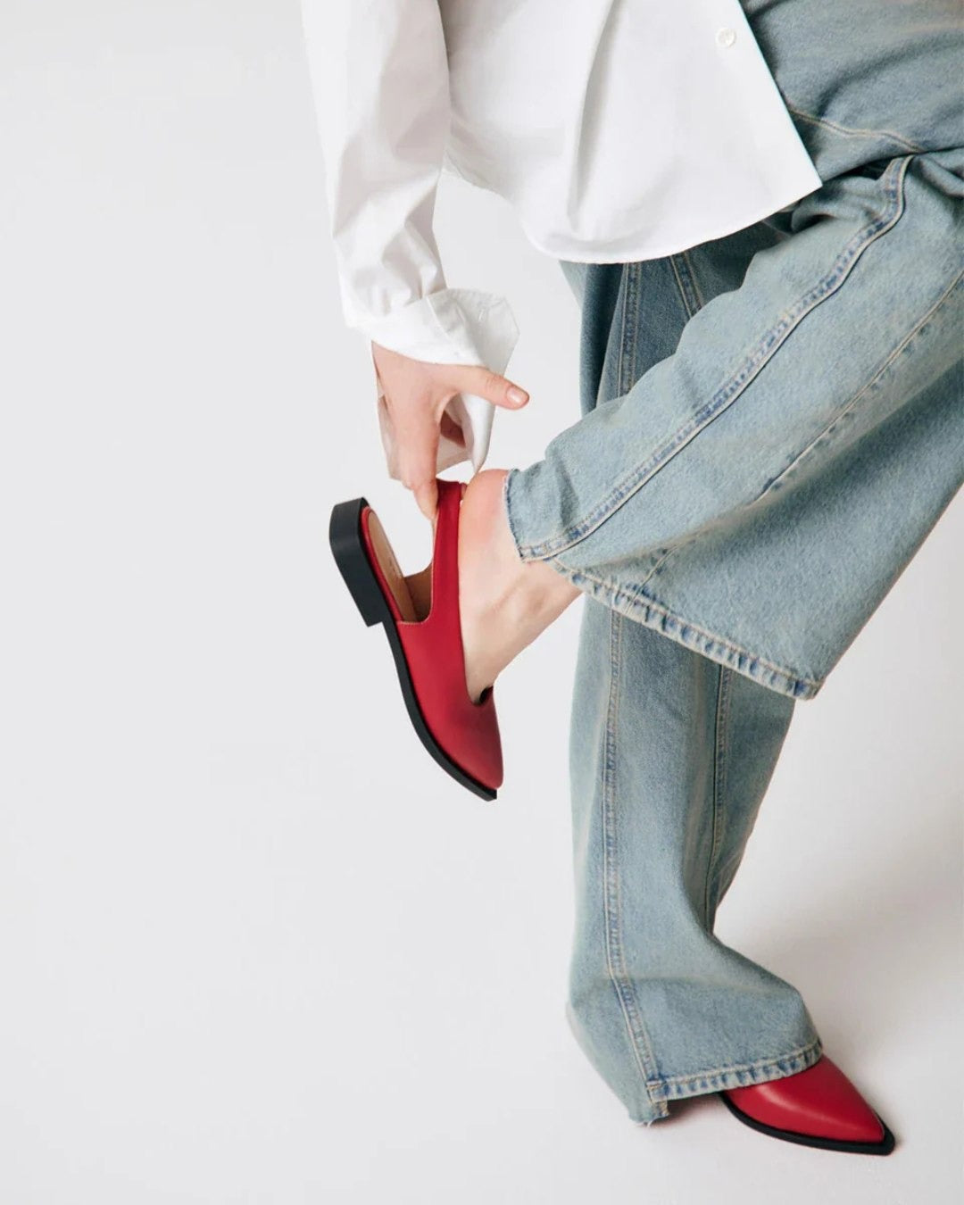 Person wearing red shoes and blue jeans on a white background